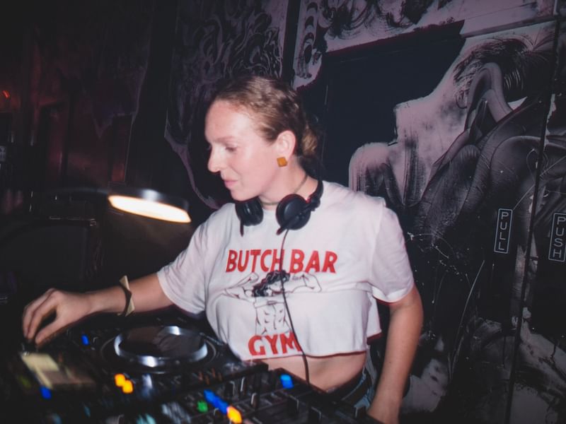 Jess working a DJ booth in a dark club.