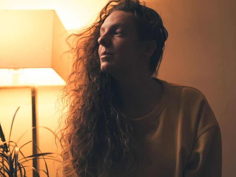 Portrait of Jess looking off to the side in warm orange light.